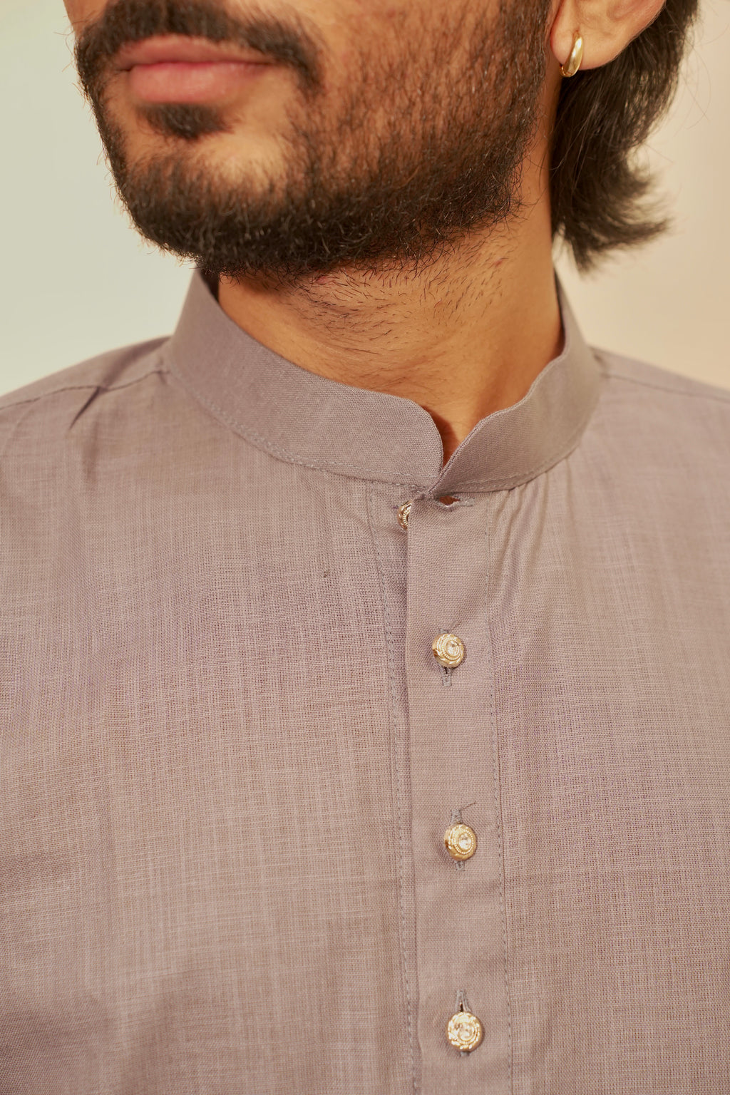 Close-up of a man wearing a light gray linen kurta with a mandarin collar and buttons.