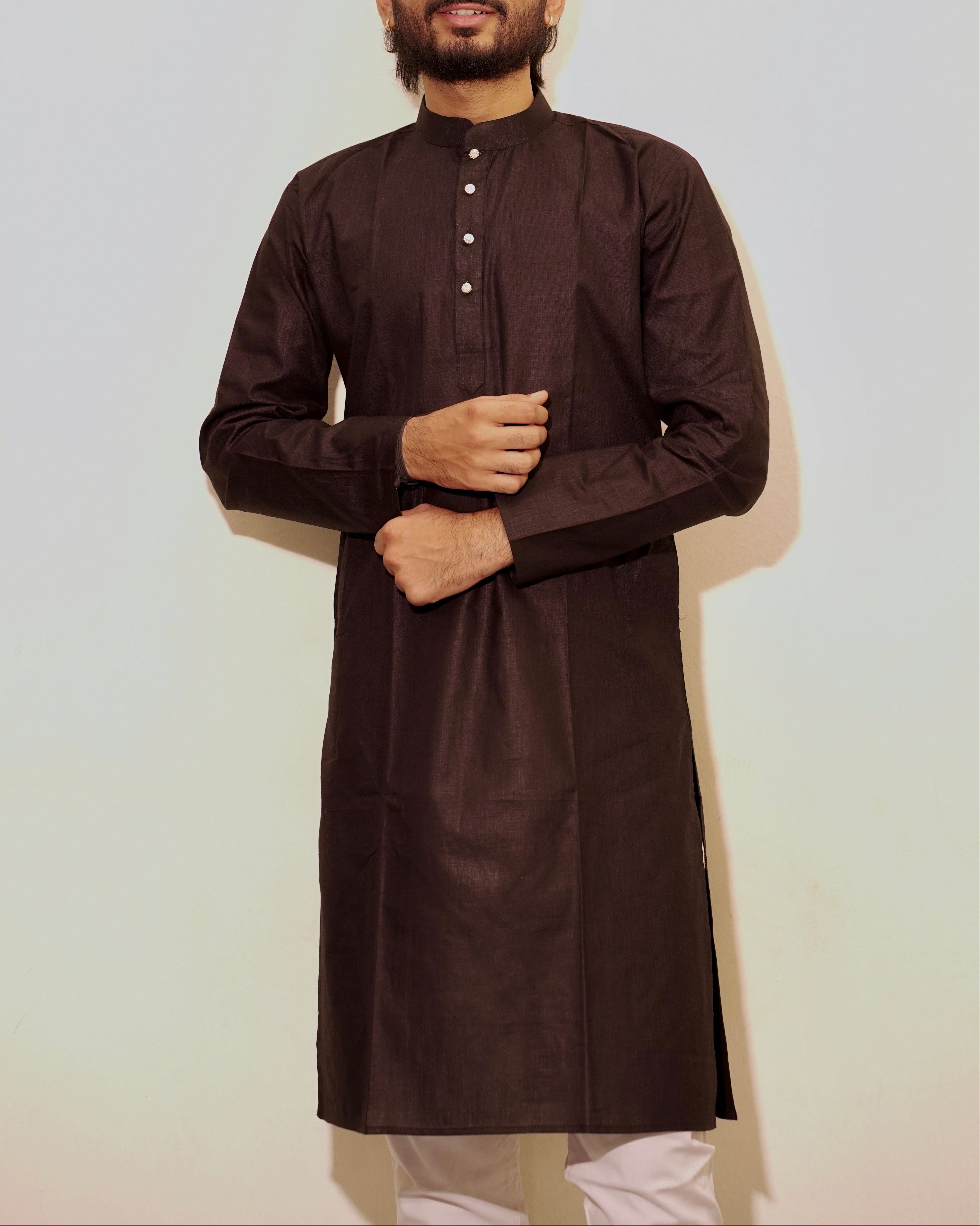 A man wearing a Black long-sleeve kurta with a band collar and small front buttons, paired with white pajama, standing against a plain light background.