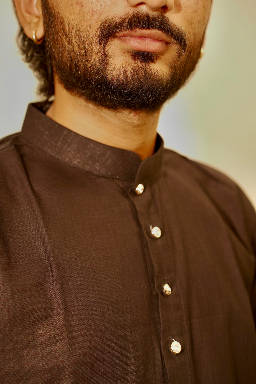 Close-up of a man wearing a black linen kurta with a mandarin collar and buttons.