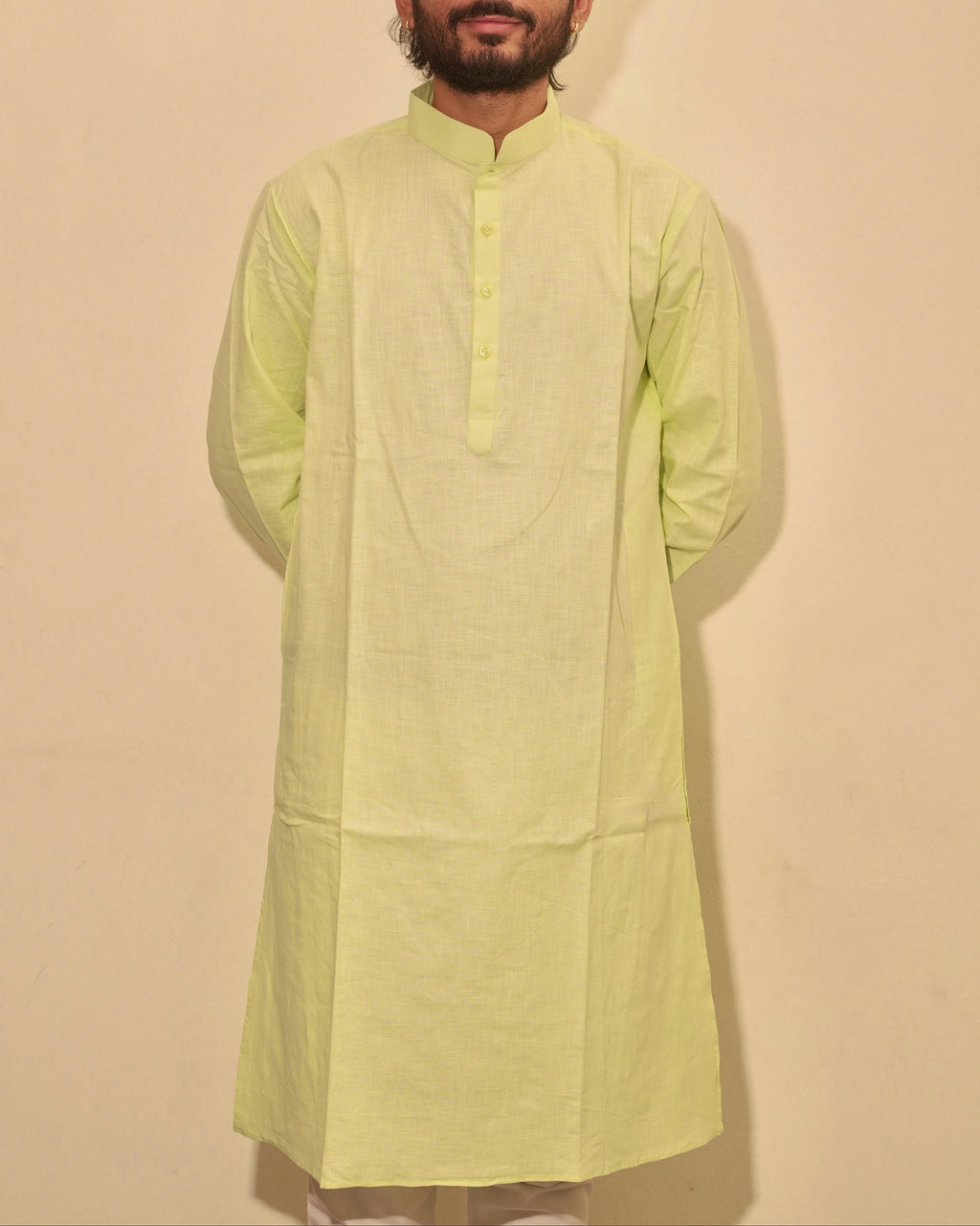 A man wearing a lime green kurta with a mandarin collar and three-quarter sleeves, standing against a plain beige background.