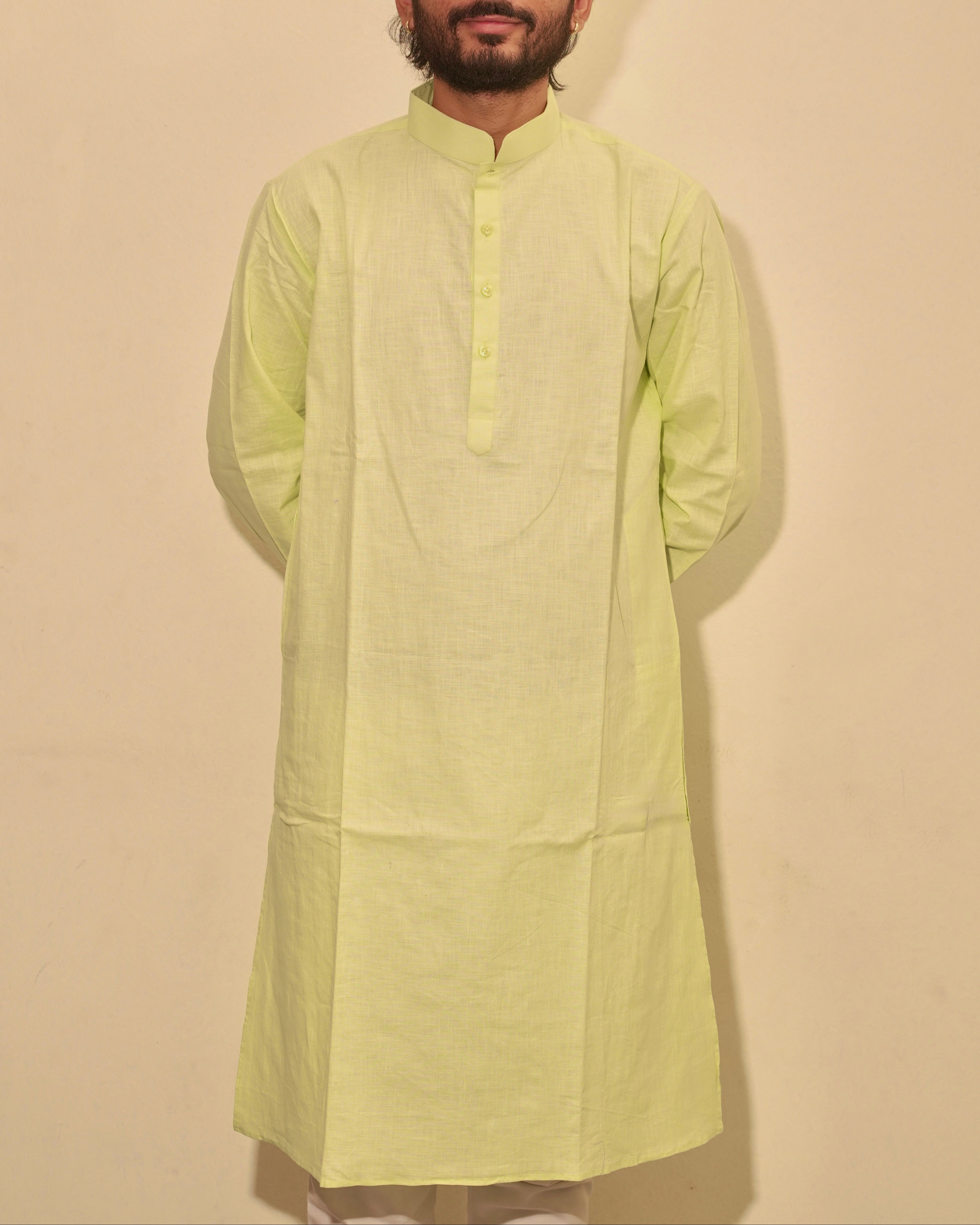 A man wearing a lime green kurta with a mandarin collar and three-quarter sleeves, standing against a plain beige background.