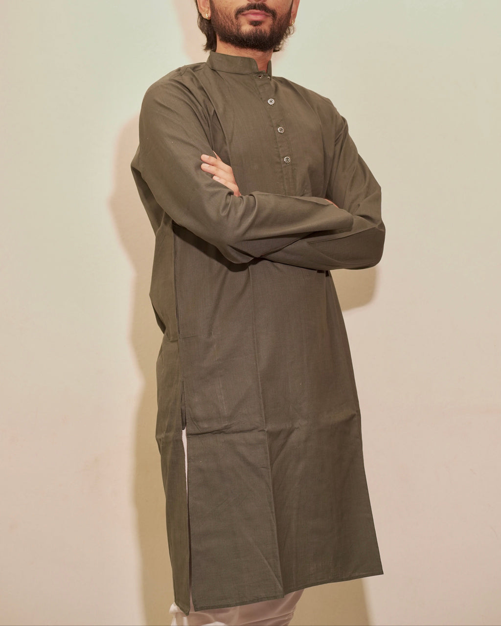 A man with a beard modeling a Bottle green long-sleeve kurta with a band collar and button placket, standing against a plain off-white background with his arms crossed.